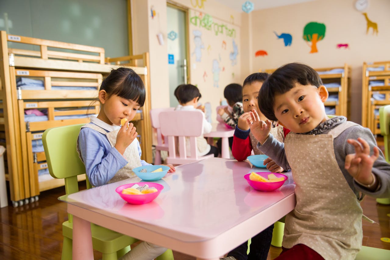 Des jeunes enfants mangent à une petite table dans une crèche.